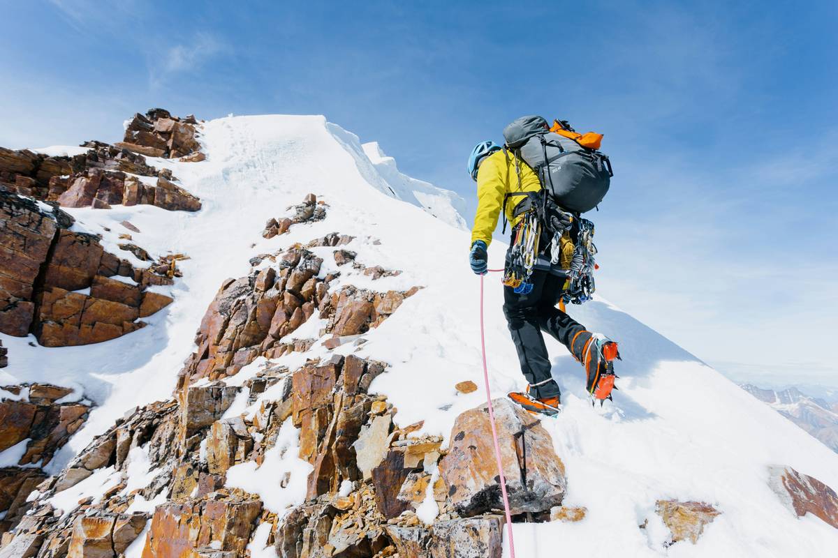 Climber placing a high-quality spring-loaded cam into a granite crack, with clear rope angles and clean carabiner orientation — climbing safety best practices