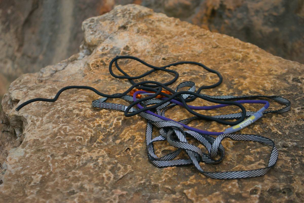 Climber placing a cam in a crack with route guard recommendations visible on gear sling